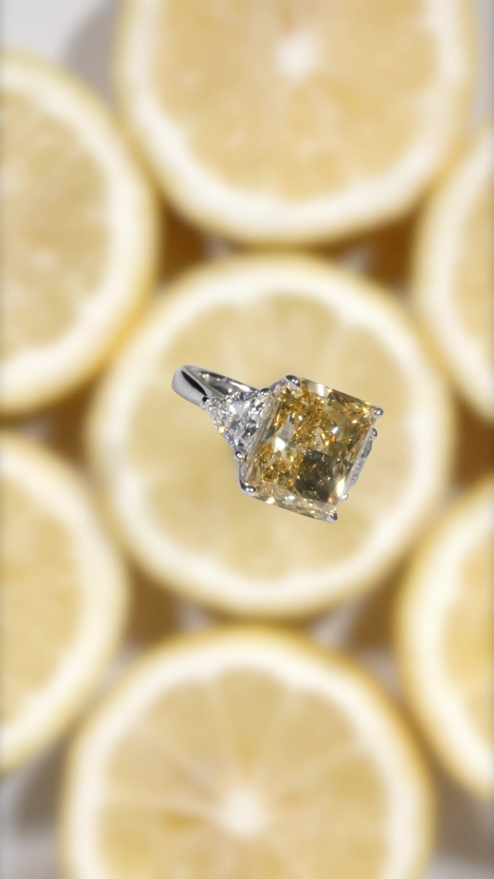 A yellow radiant cut diamond ring on sliced lemons